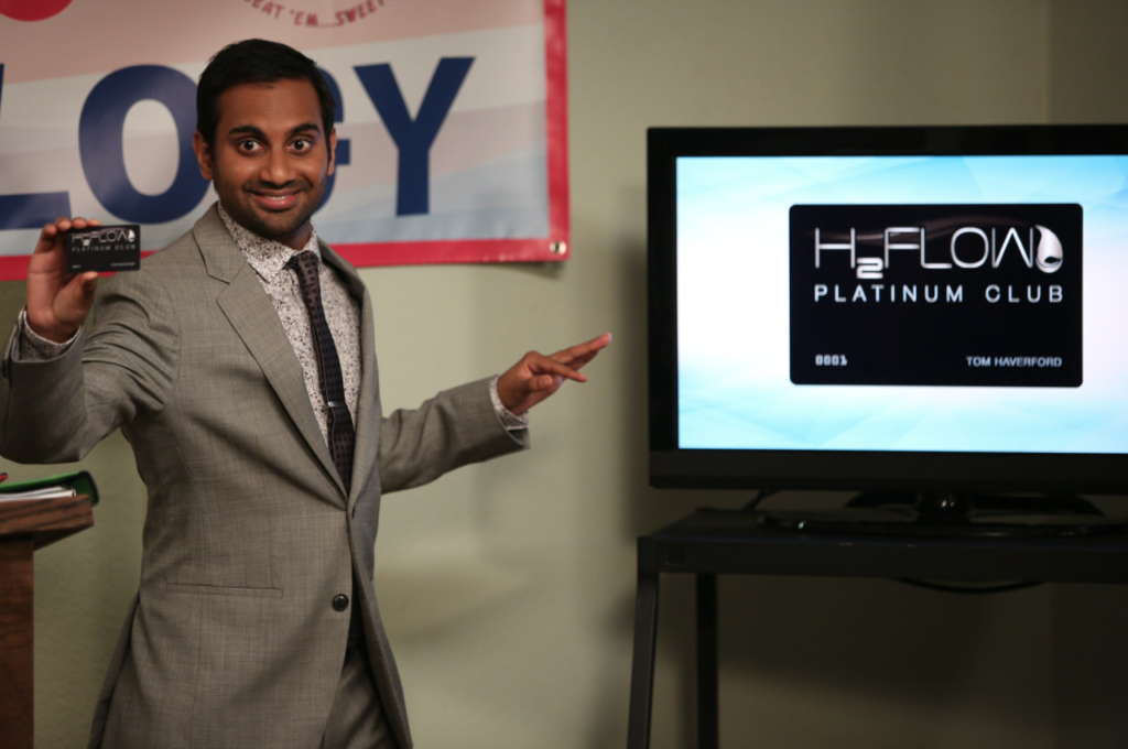 Photograph of "Parks and Rec" character pointing at a television monitor as he explains Sparkle Points.